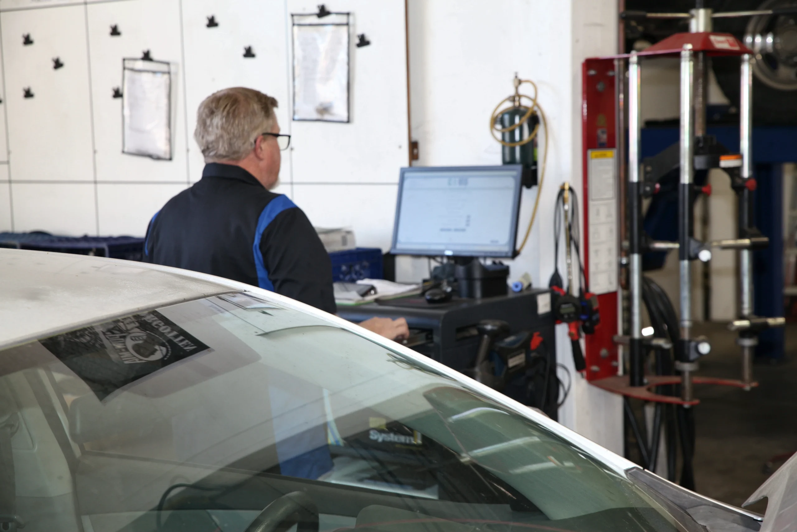 Technician with a sedan in the shop bay