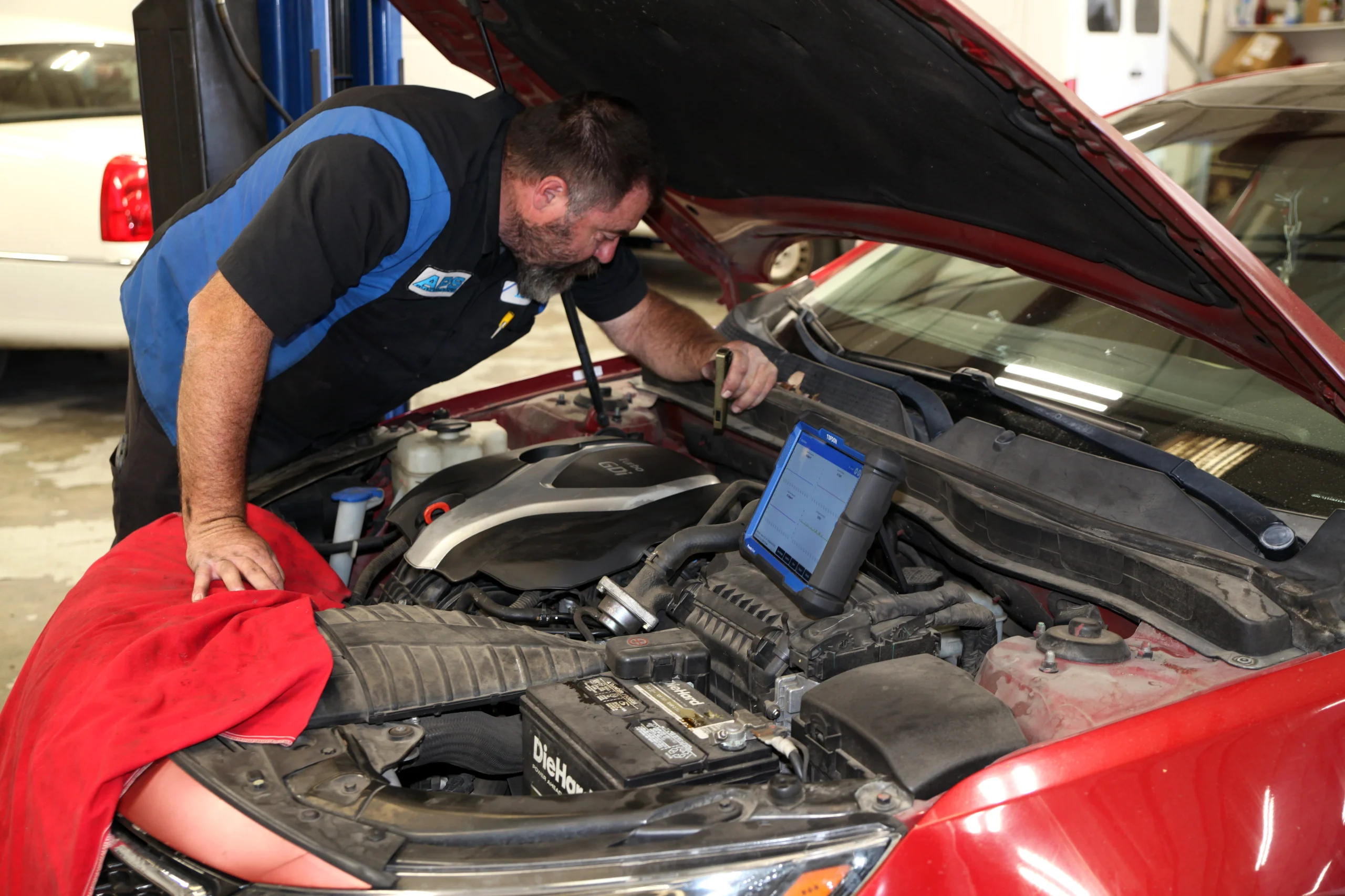 Technician talking with a customer beside an open hood in the shop